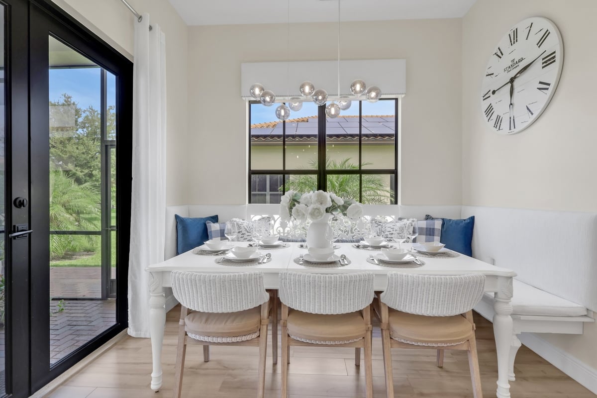 bright breakfast nook with white banquette dining table and wall clock in naples fl full home remodel