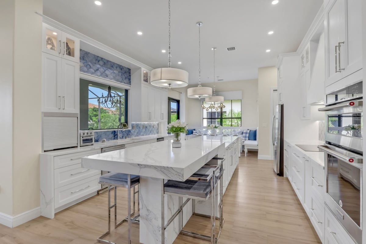 bright white kitchen with waterfall island pendant lights and stainless appliances in naples fl full home remodel