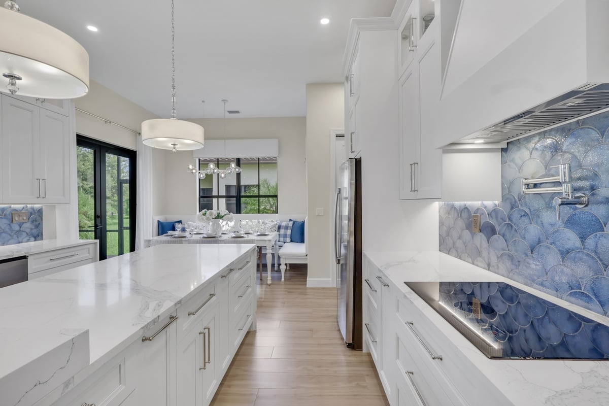 custom white kitchen with blue tile backsplash cooktop and large island in naples fl full home remodel