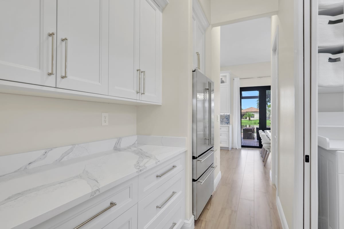 full home remodel butlers pantry with white cabinetry and marble look counters in naples fl