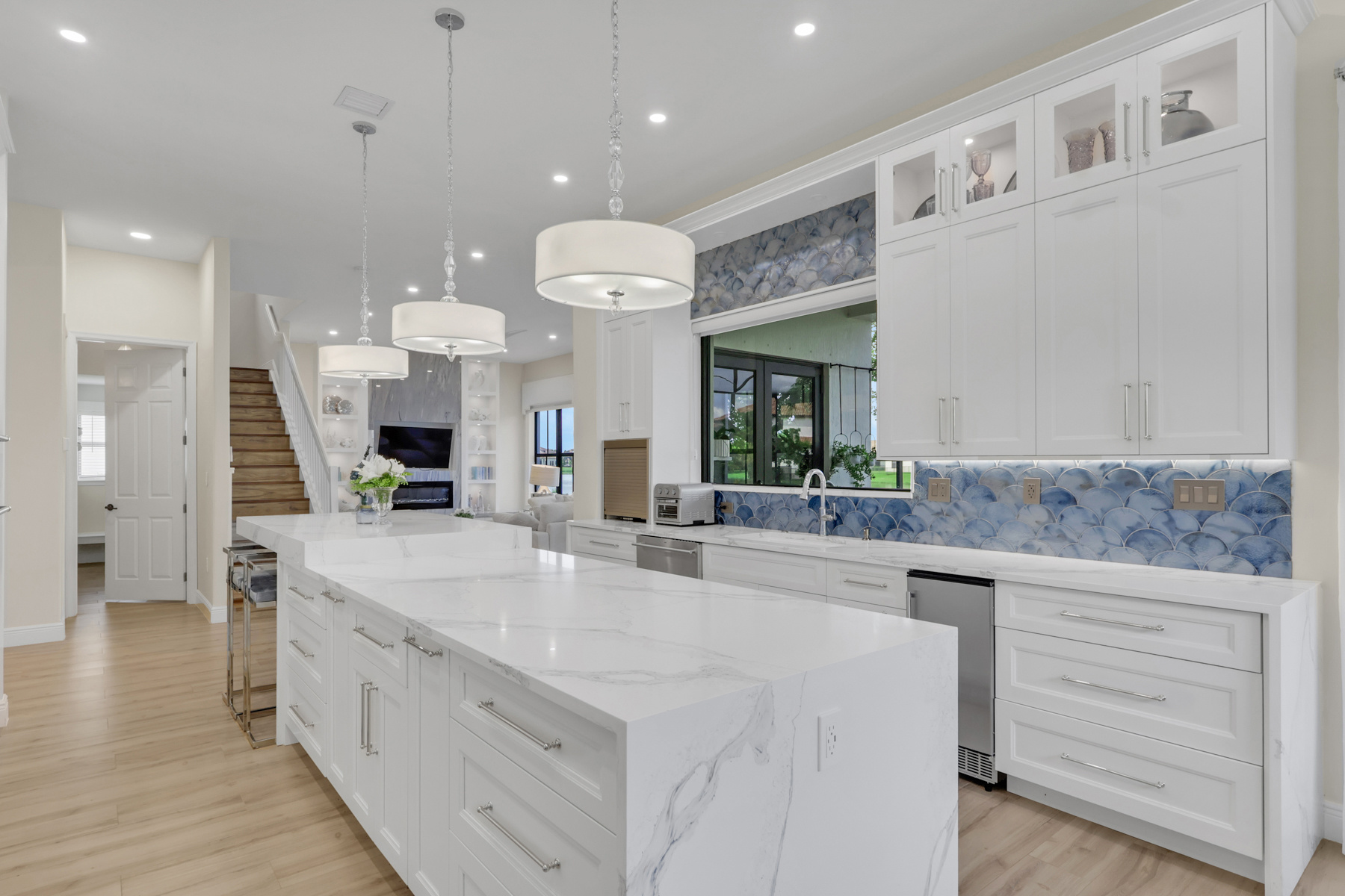 full home remodel kitchen with large marble look island and blue backsplash in naples fl
