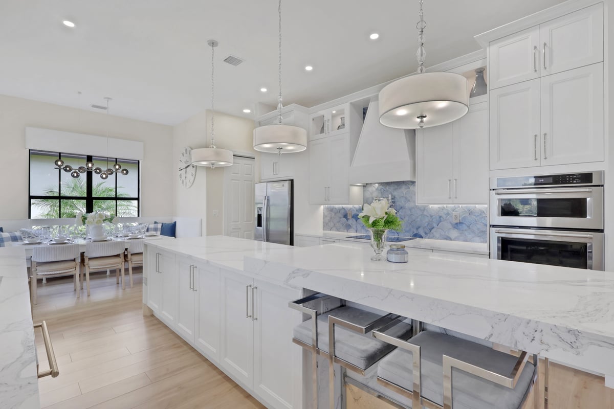 full home remodel kitchen with waterfall island pendant lights and white cabinetry in naples fl