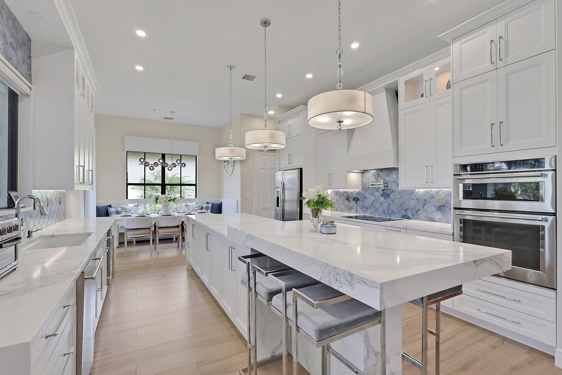 full home remodel kitchen with white cabinetry waterfall island and blue backsplash in naples fl