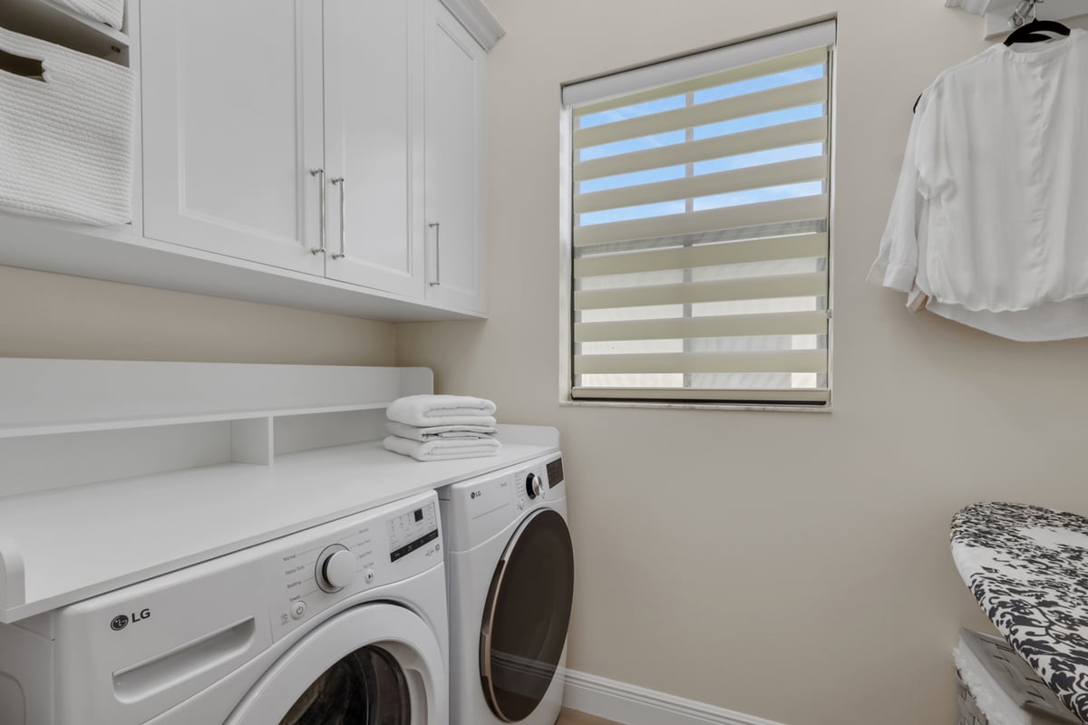 full home remodel laundry room with white cabinetry window and ironing area in naples fl