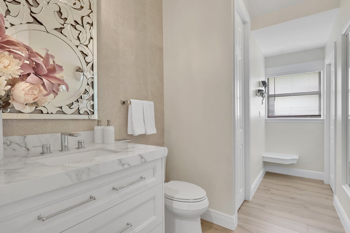full home remodel powder bathroom with marble vanity and decorative mirror in naples fl