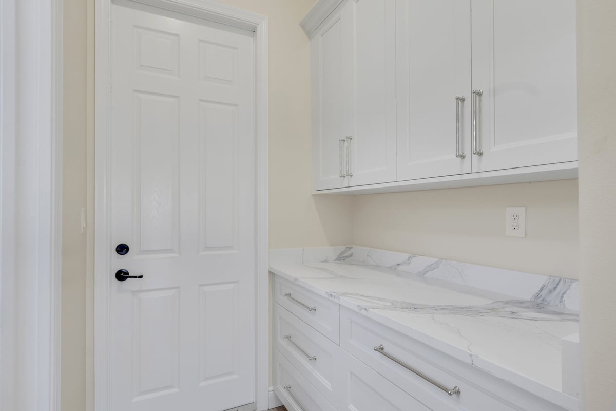 full home remodel utility storage with white cabinets and marble look counter in naples fl