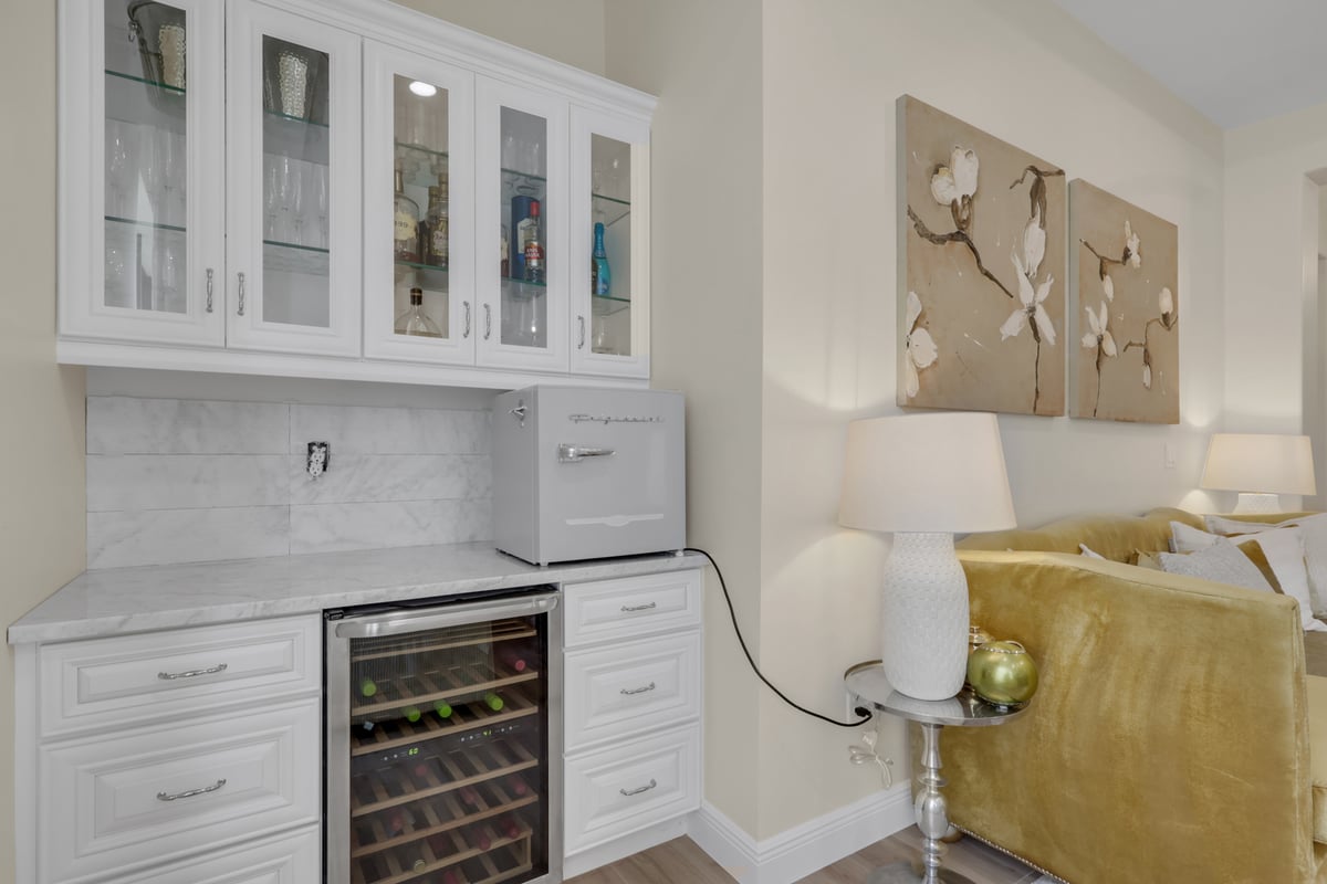 full home remodel wet bar with glass cabinets wine cooler and marble backsplash in naples fl