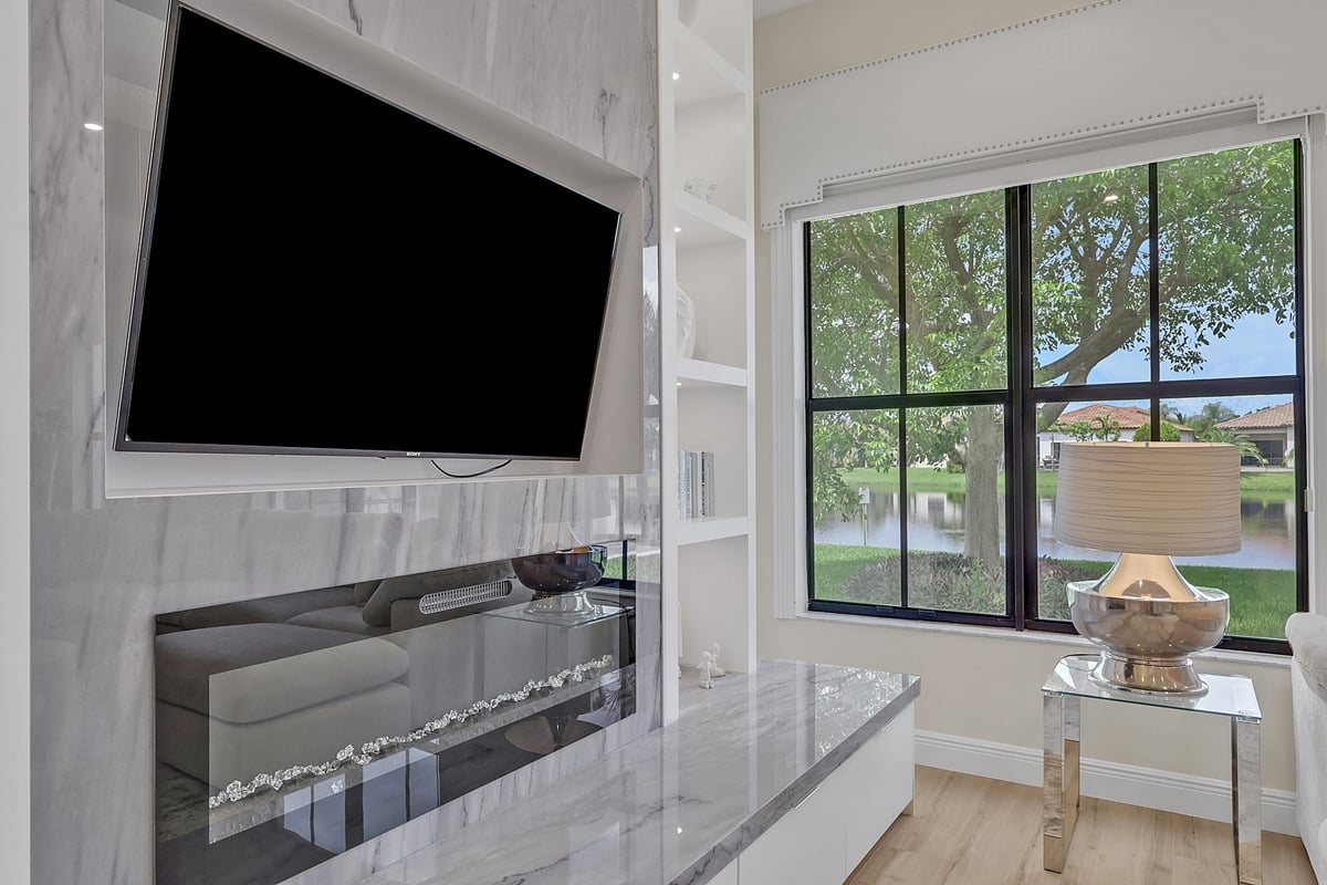 marble fireplace with mounted tv and lake view window in naples fl full home remodel