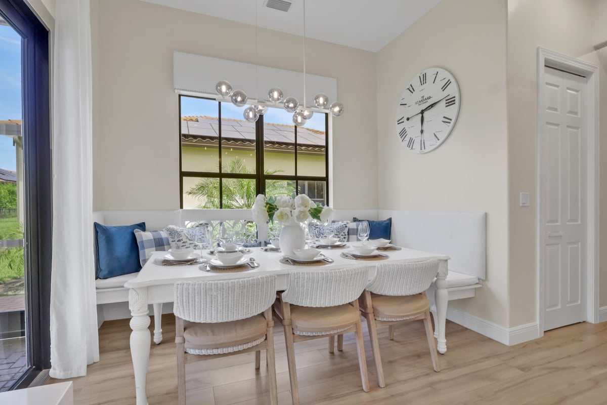 white breakfast nook with built in banquette and modern globe chandelier in naples fl full home remodel