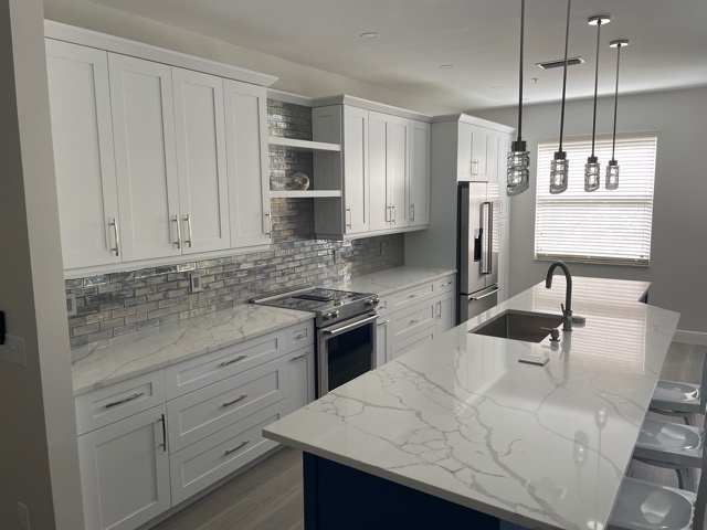 kitchen and bathroom remodel with white shaker cabinets quartz island and tile backsplash in naples fl