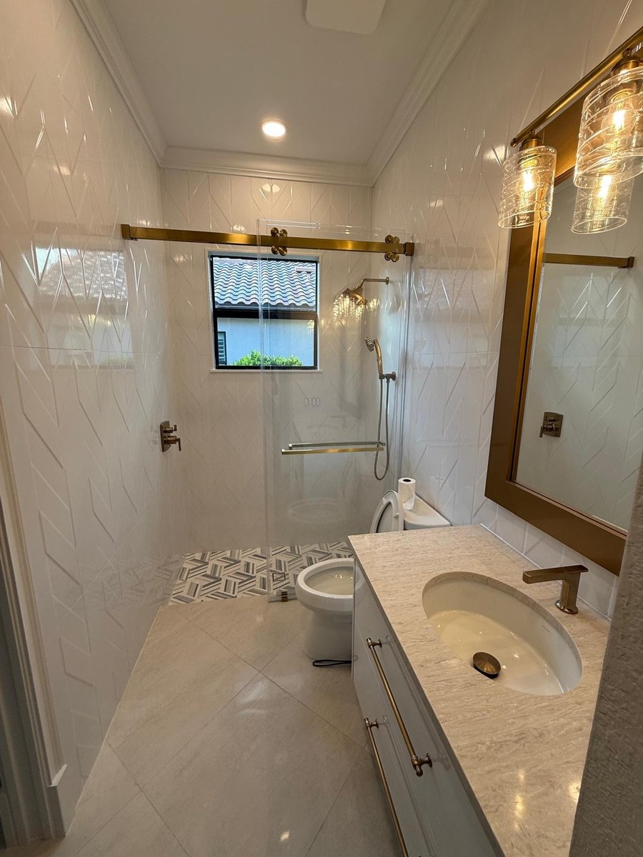 full home remodel bathroom with glass shower white tile and brass fixtures in naples fl