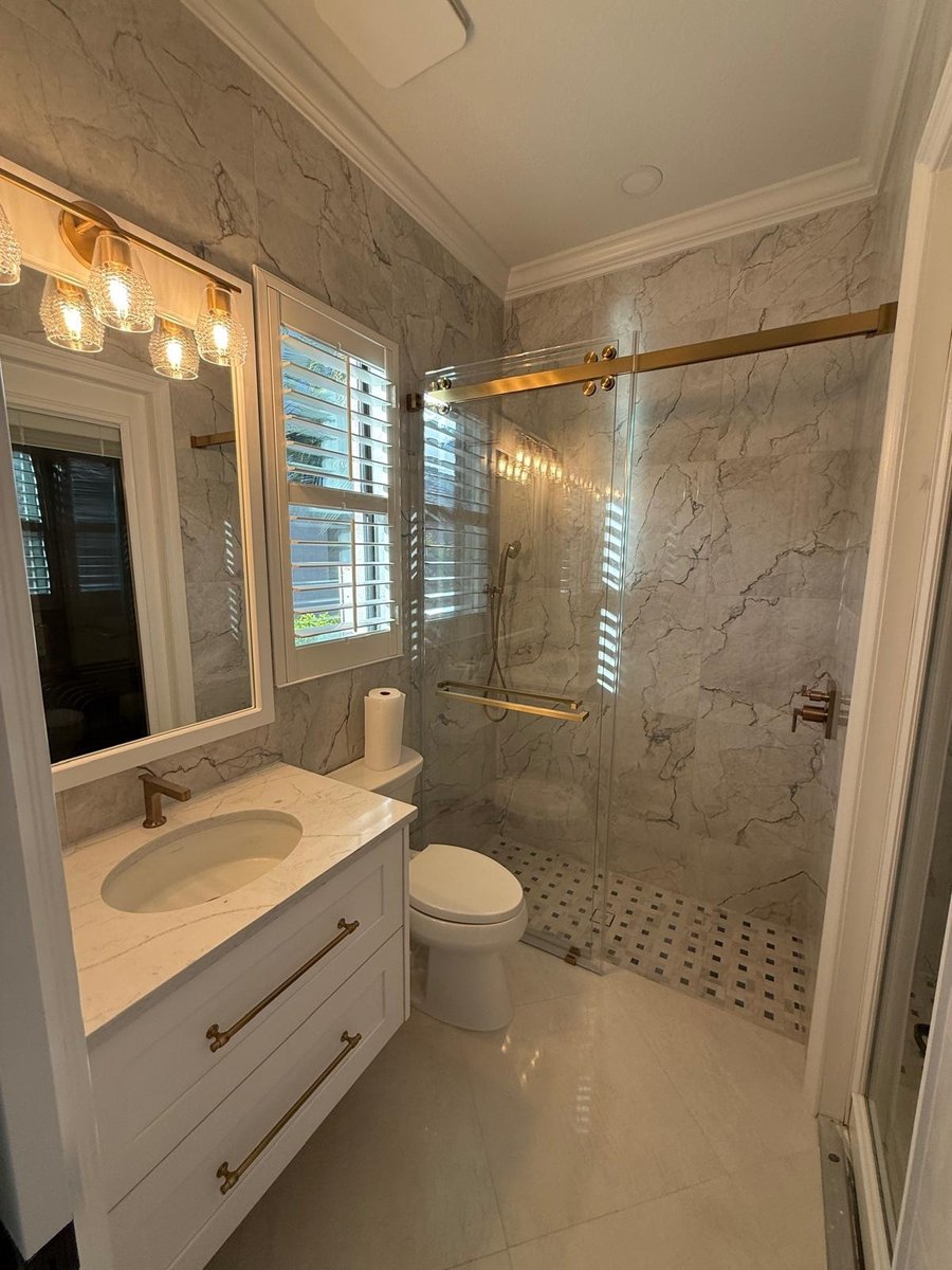 full home remodel bathroom with white vanity marble look shower and brass fixtures in naples fl