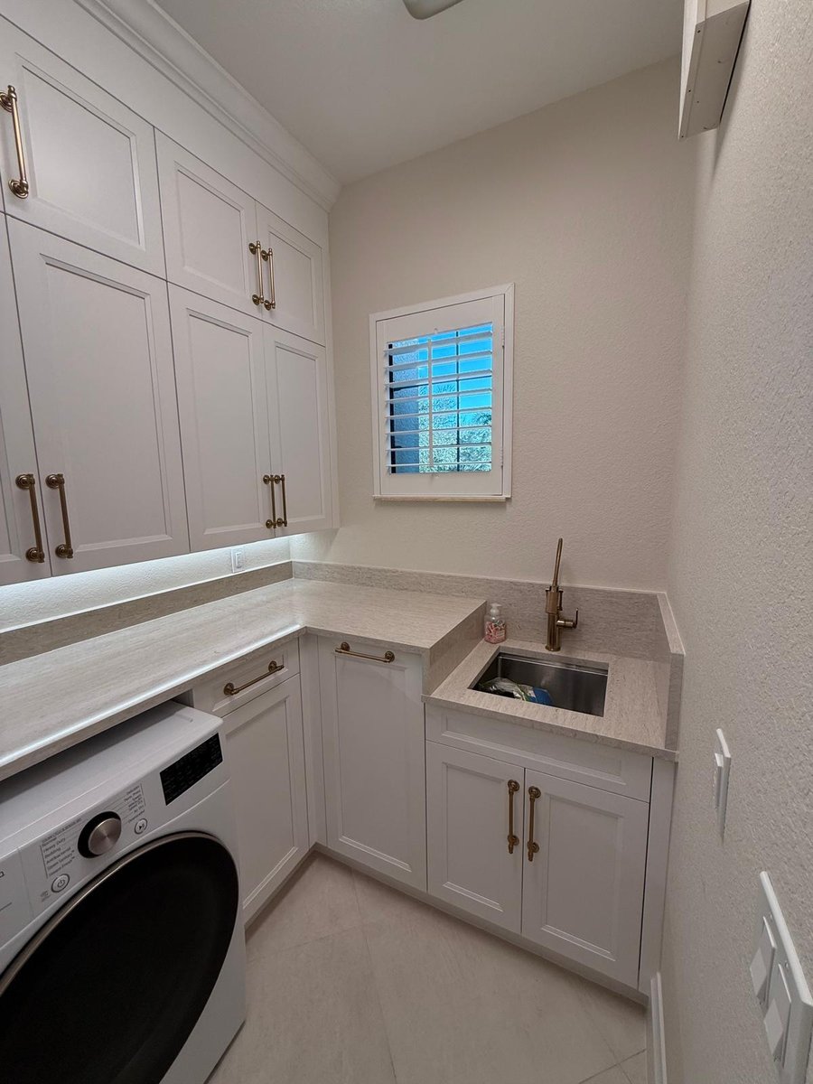 full home remodel laundry room with utility sink white cabinets and brass hardware in naples fl