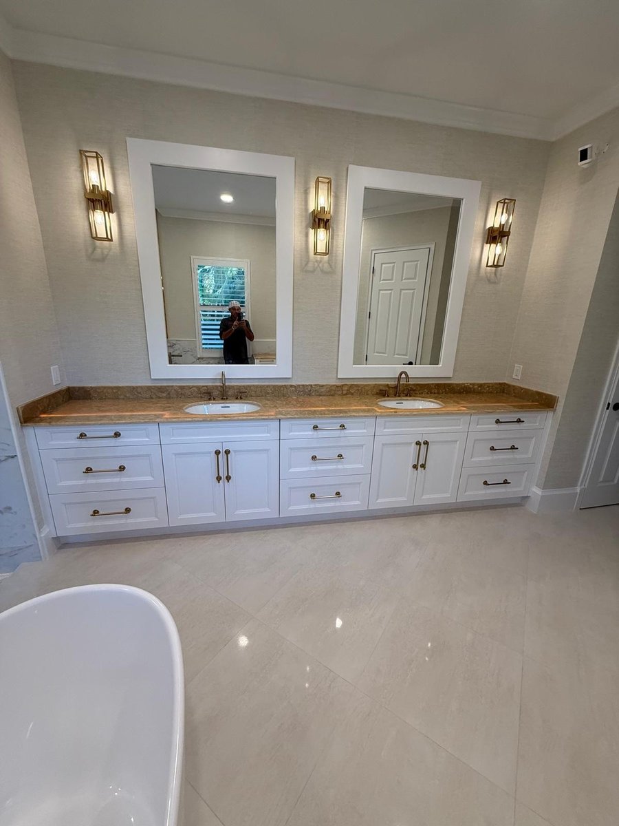 full home remodel primary bathroom with double vanity white cabinetry and brass fixtures in naples fl