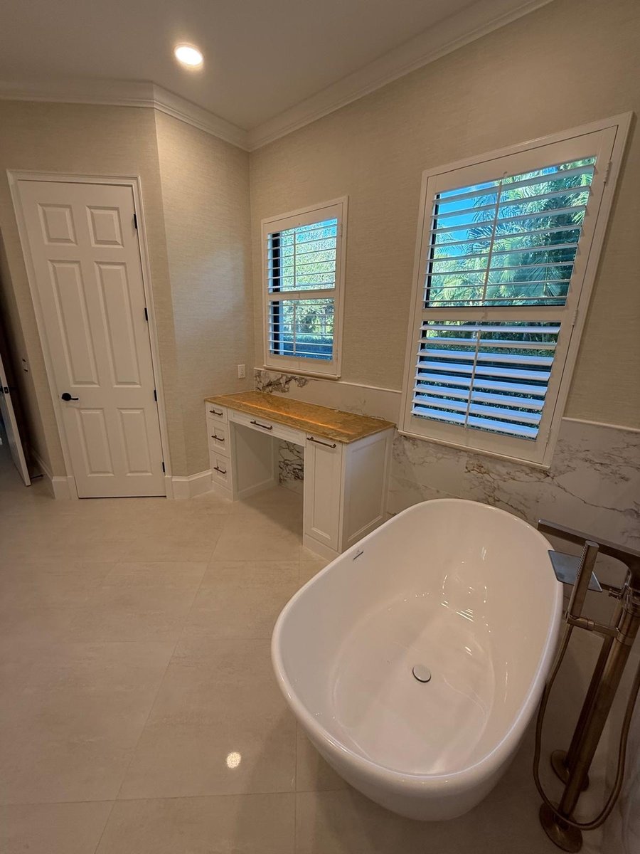 full home remodel primary bathroom with freestanding tub custom desk and plantation shutters in naples fl