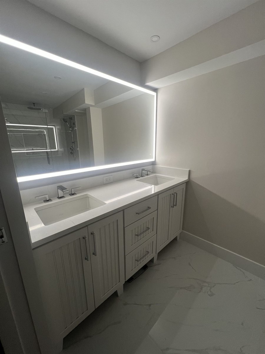 double vanity with backlit mirror and marble floor primary bathroom renovation