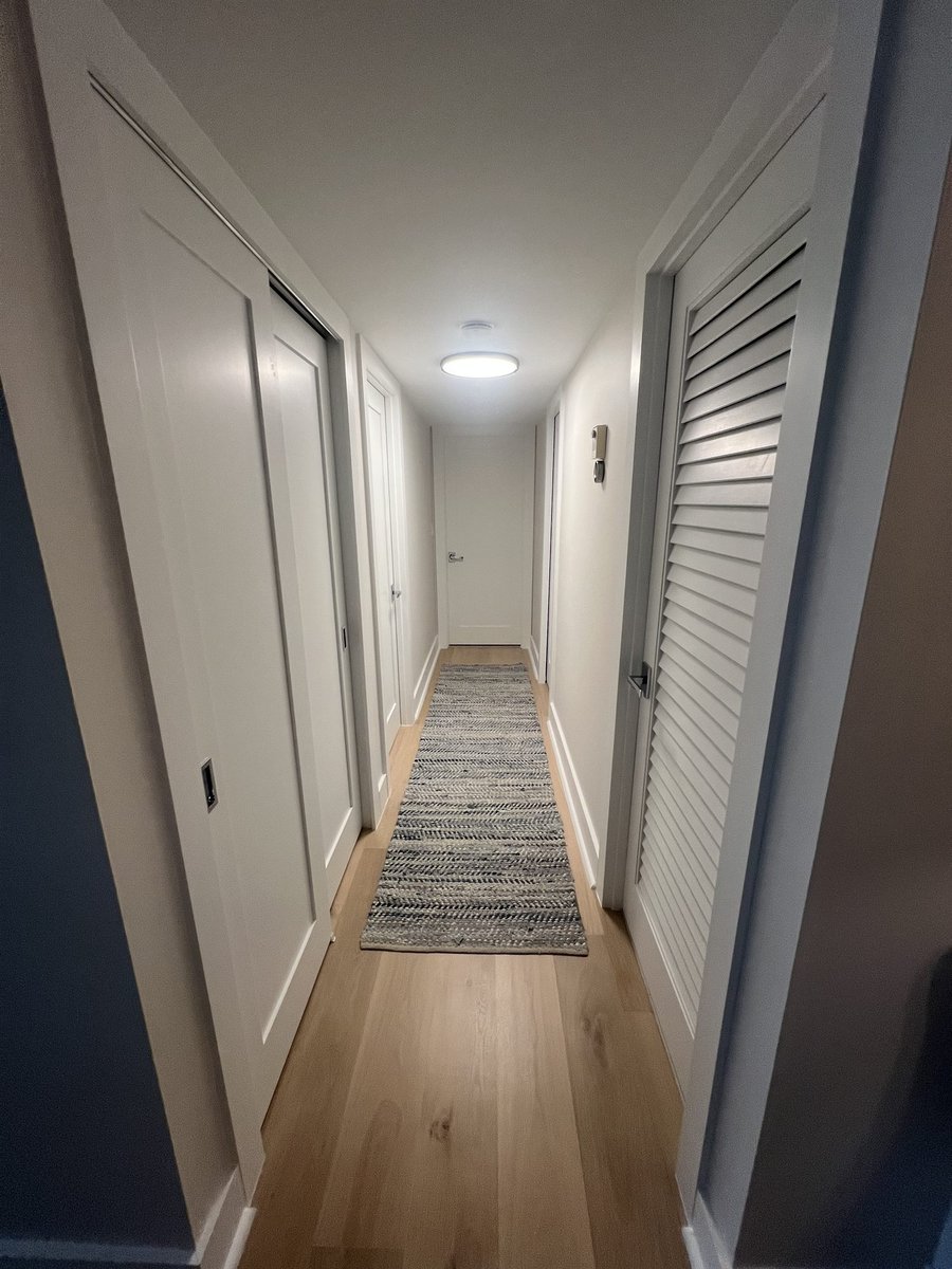 hallway with wood flooring and louvered closet doors renovation