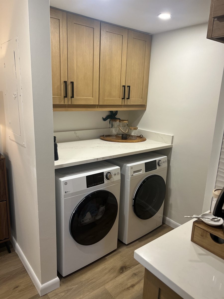 laundry area with white front load washer and dryer under wood cabinets kitchen remodel