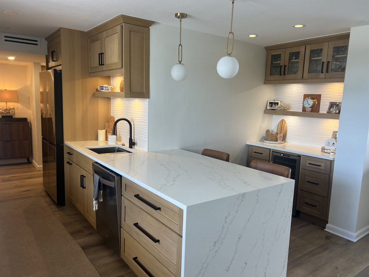 waterfall island with black dishwasher and beverage fridge and glass upper cabinets kitchen remodel