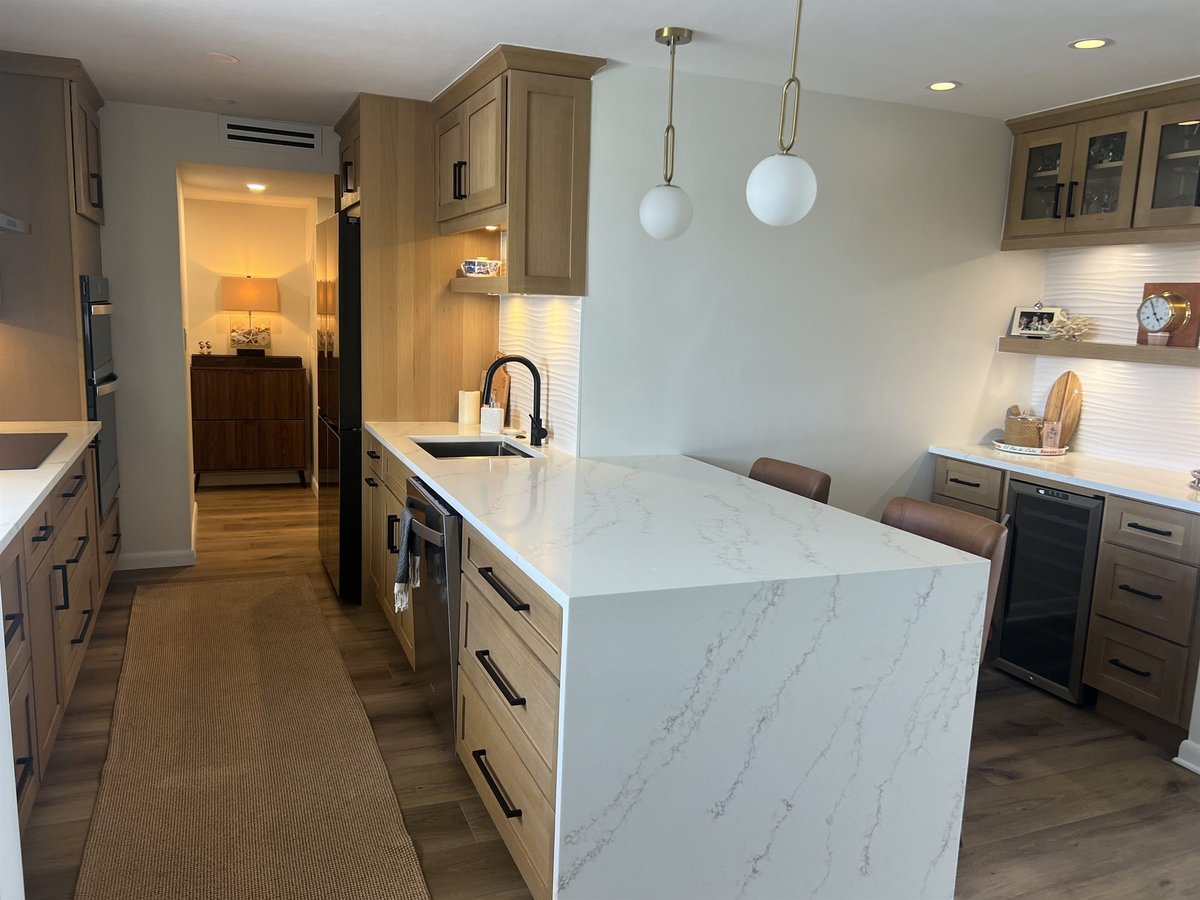 white quartz waterfall island with black faucet and glass front cabinets kitchen remodel