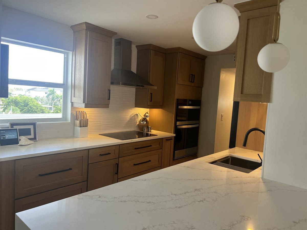 wood cabinets and white quartz counters with induction cooktop under window kitchen remodel