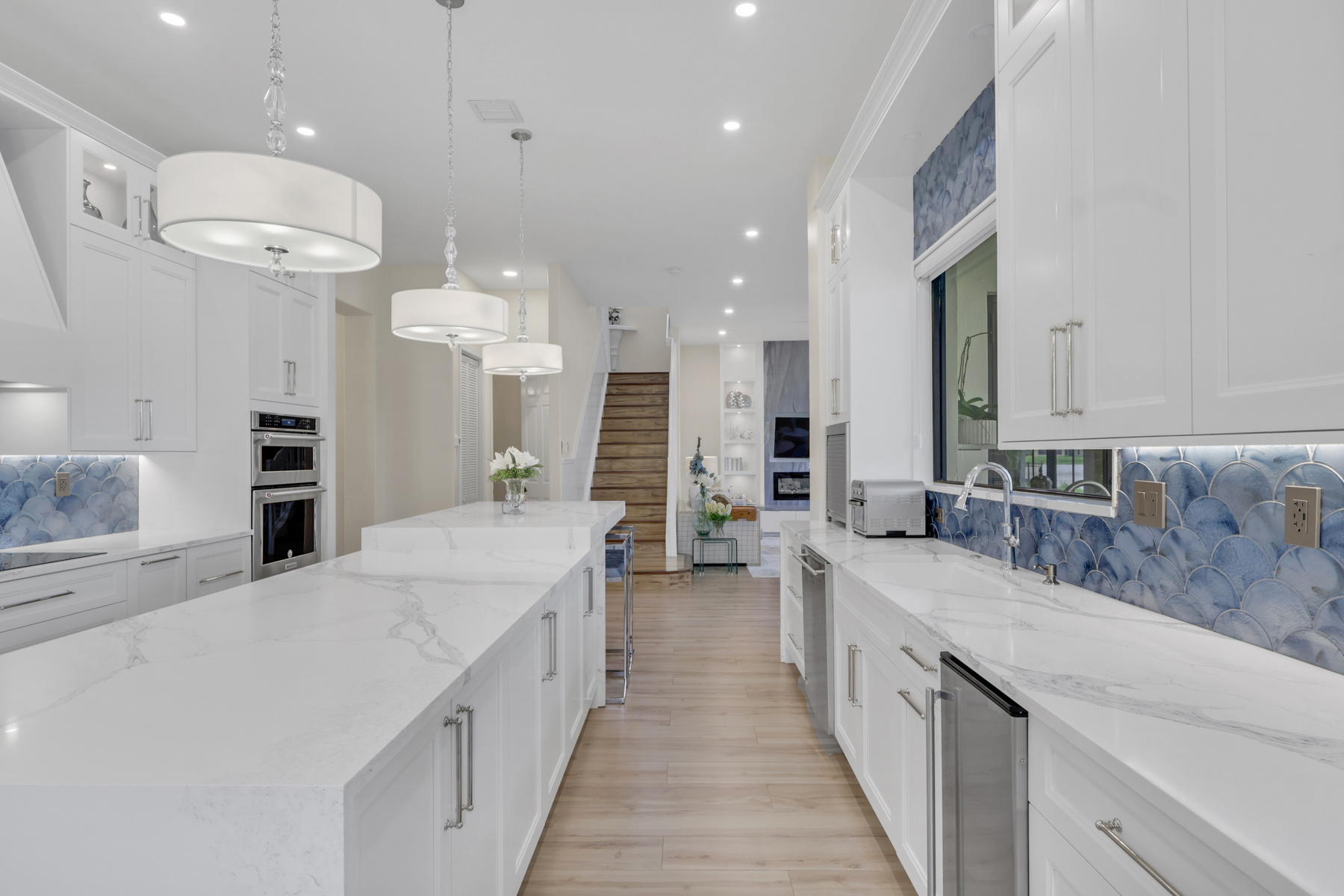 full home remodel kitchen with double island white cabinets and blue backsplash in naples fl